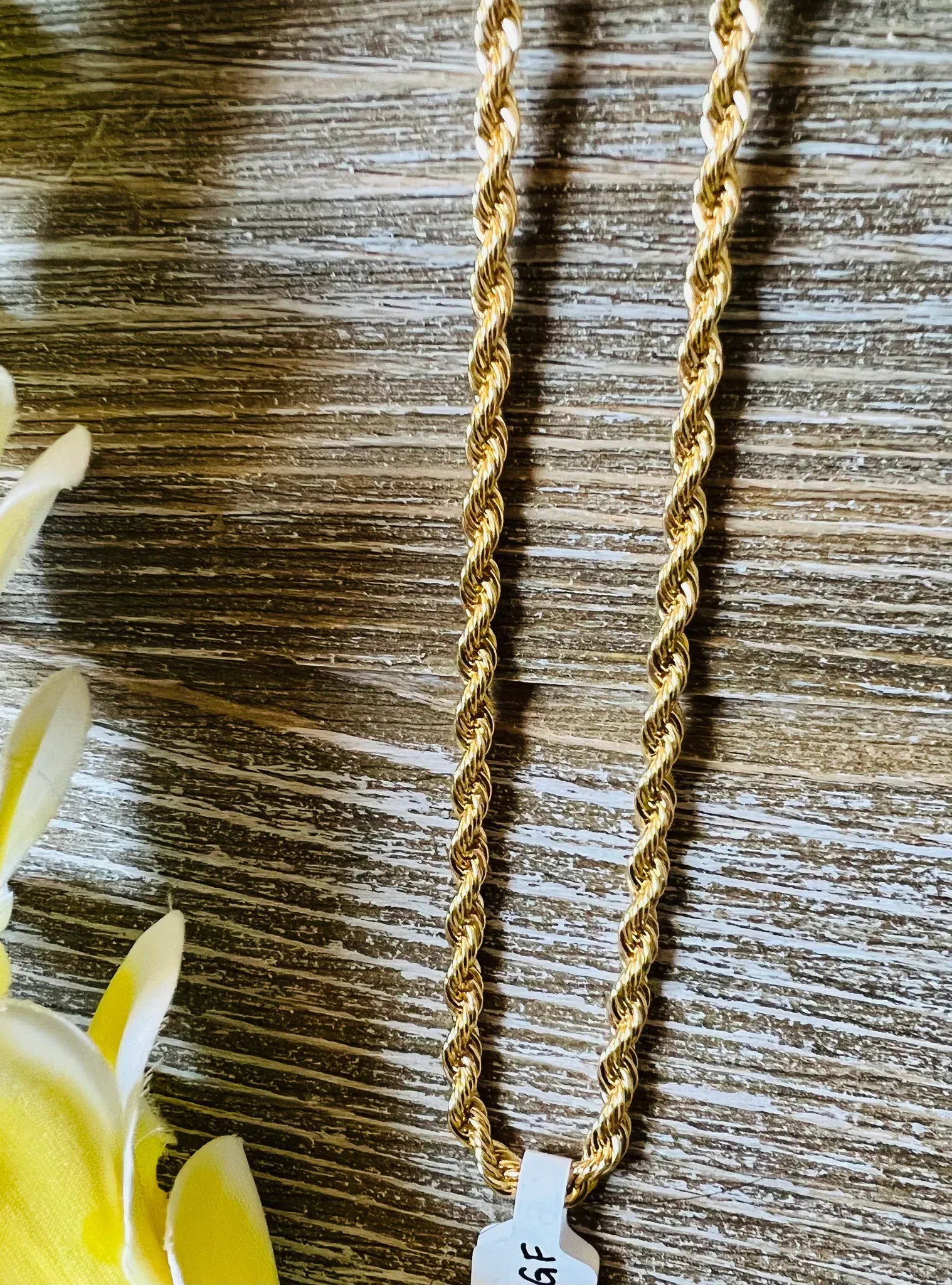 Gold wheat chain necklaces of varying thicknesses on a dark surface.