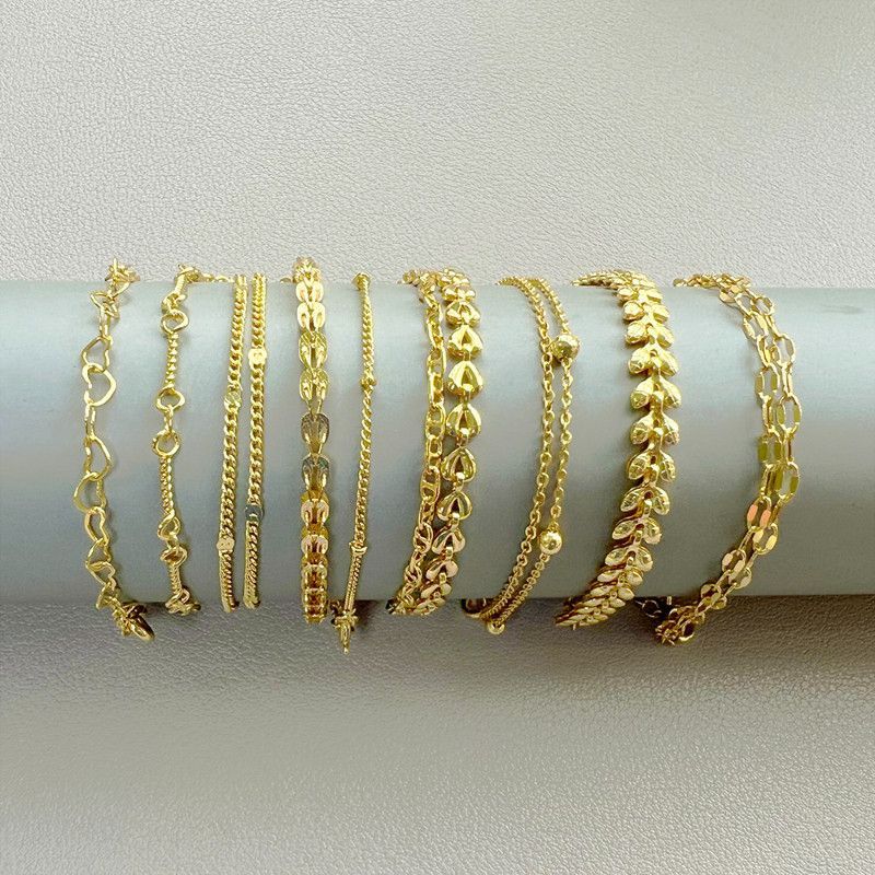 Nine gold bracelets displayed on a gray cylinder.
