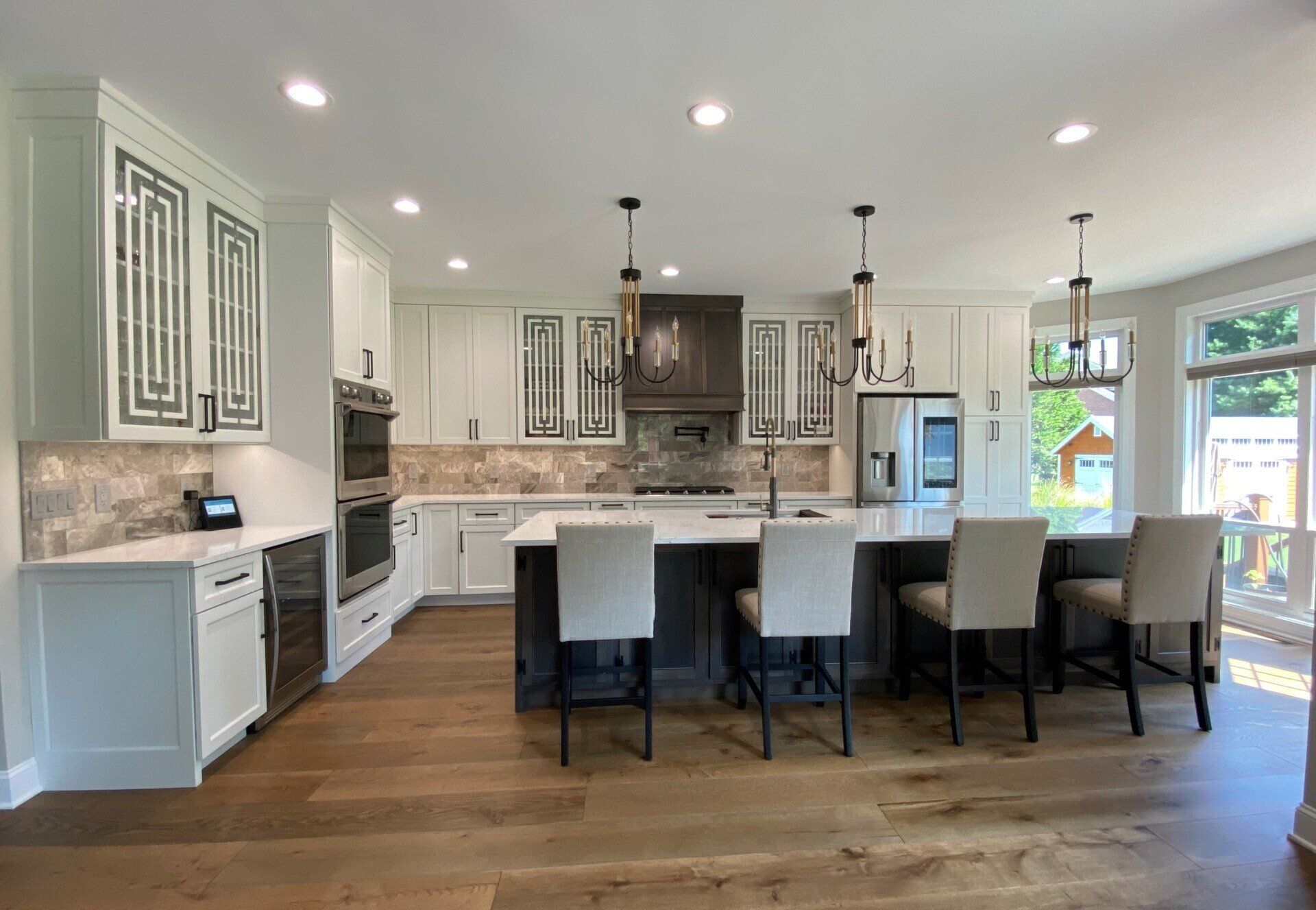 A kitchen with white cabinets , stainless steel appliances , hardwood floors and a large island.