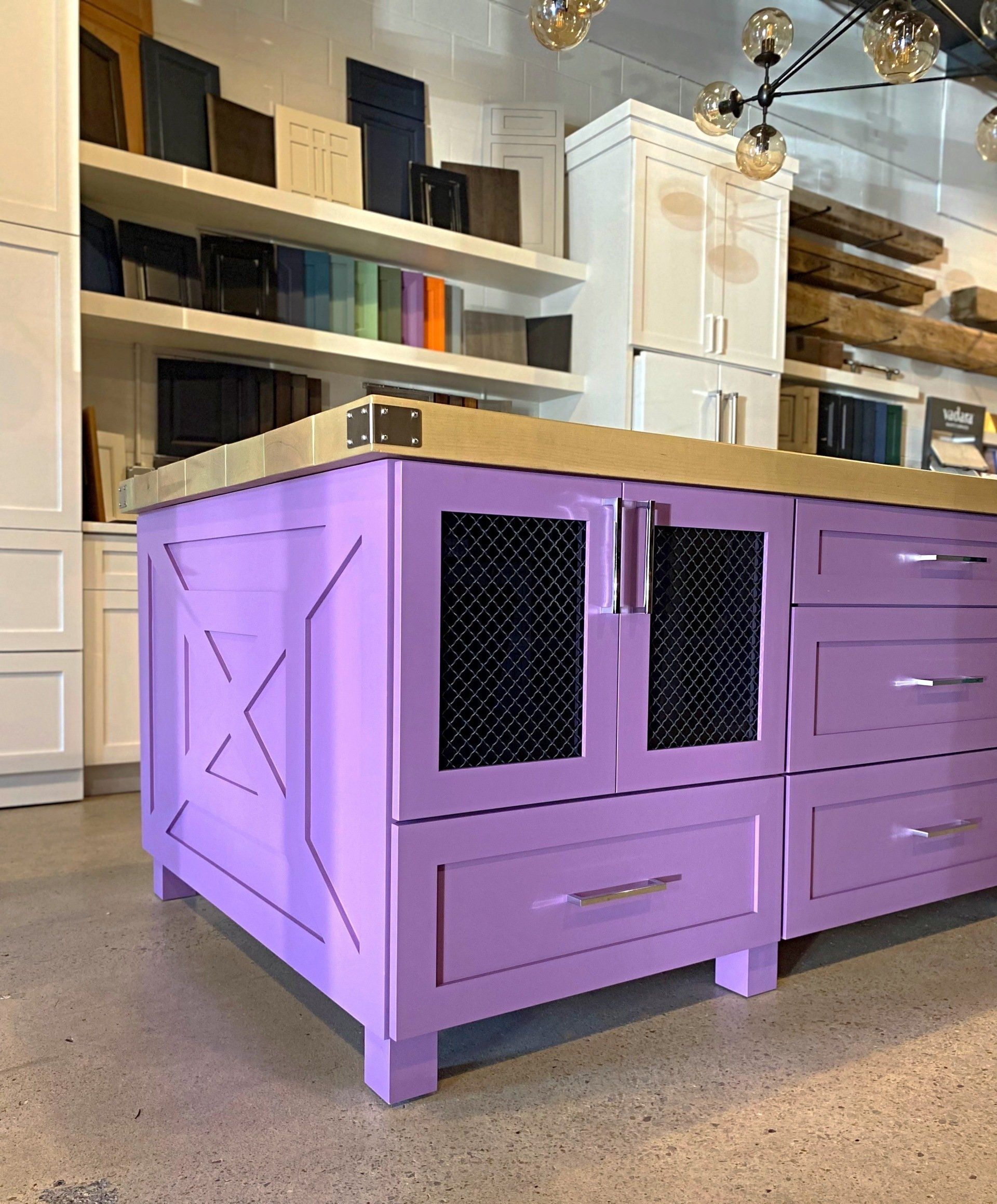 A kitchen with purple cabinets and drawers and a purple island