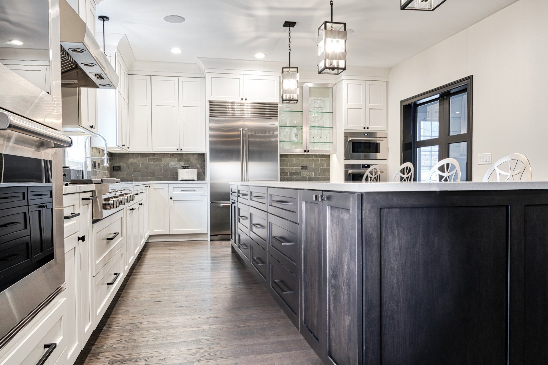 A kitchen with white cabinets , stainless steel appliances , and a large island.