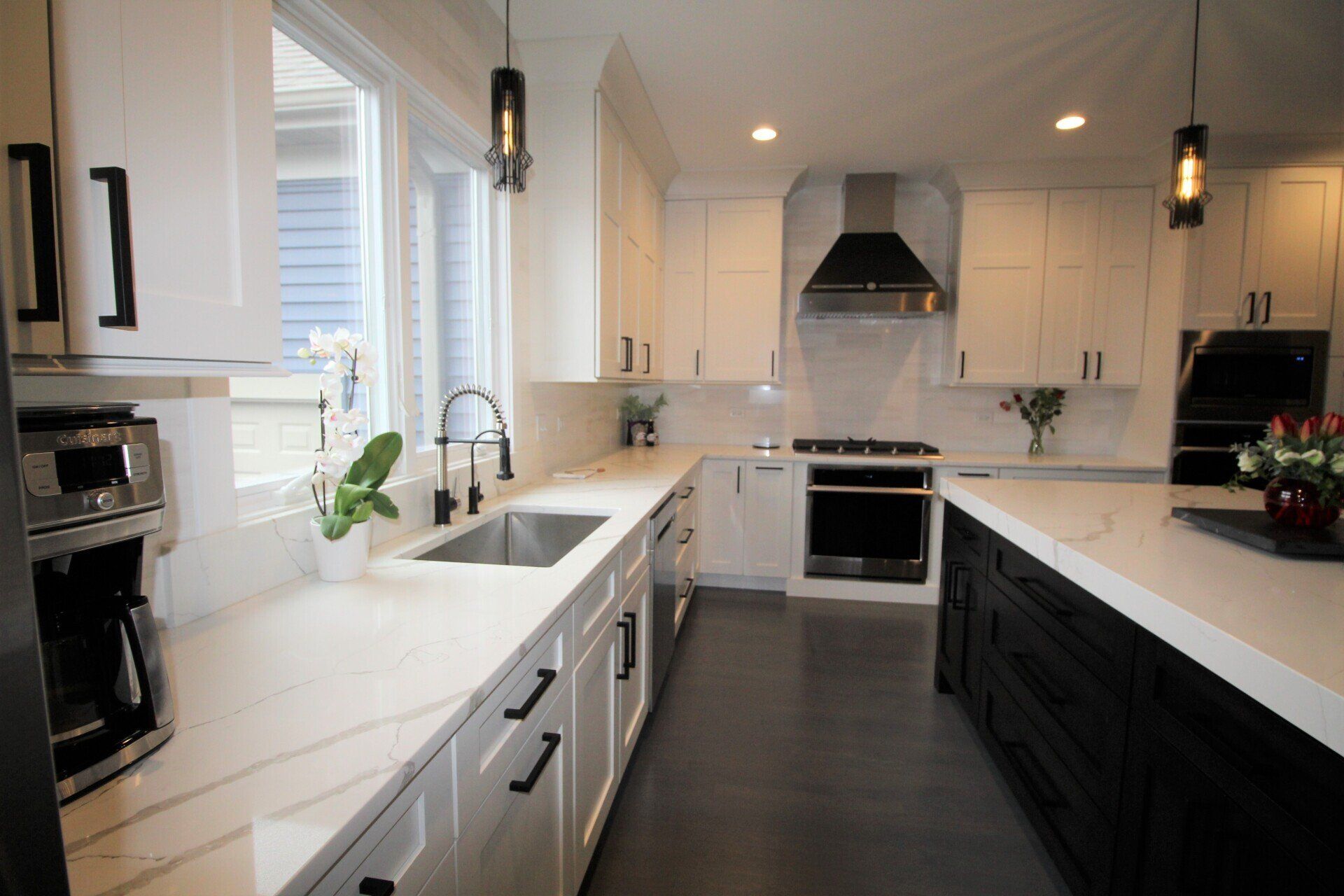 A kitchen with white cabinets and black counter tops