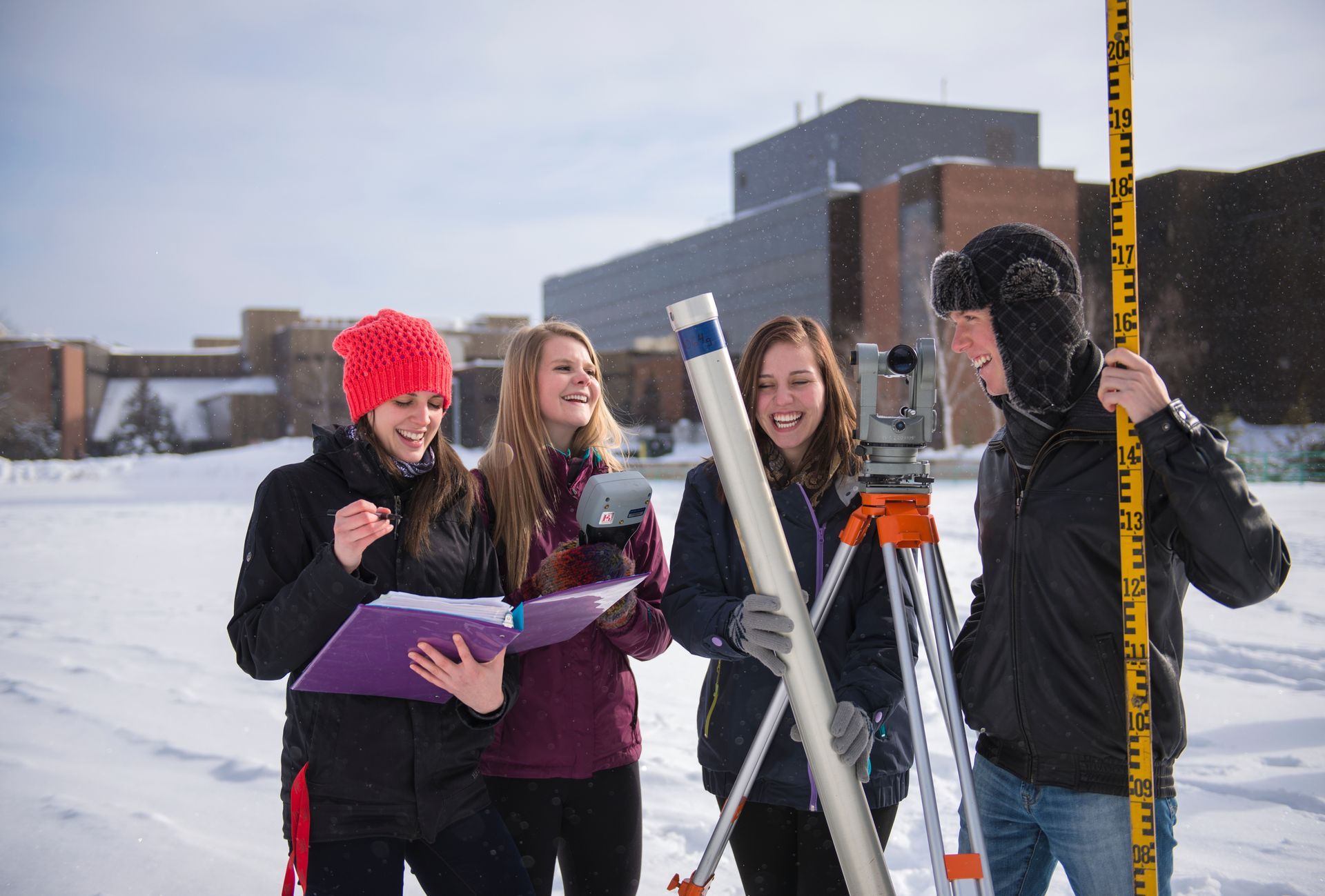 A group of people are standing in the snow looking at something.