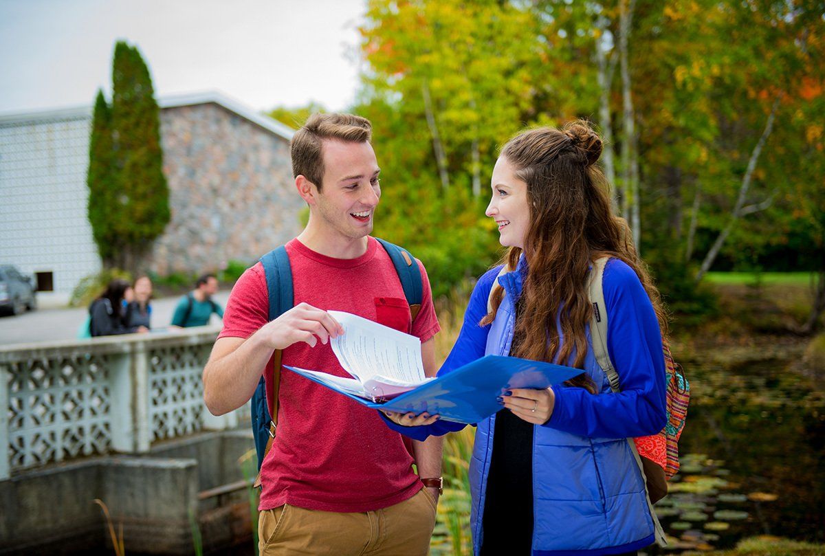 A man and a woman are standing next to each other looking at a piece of paper.