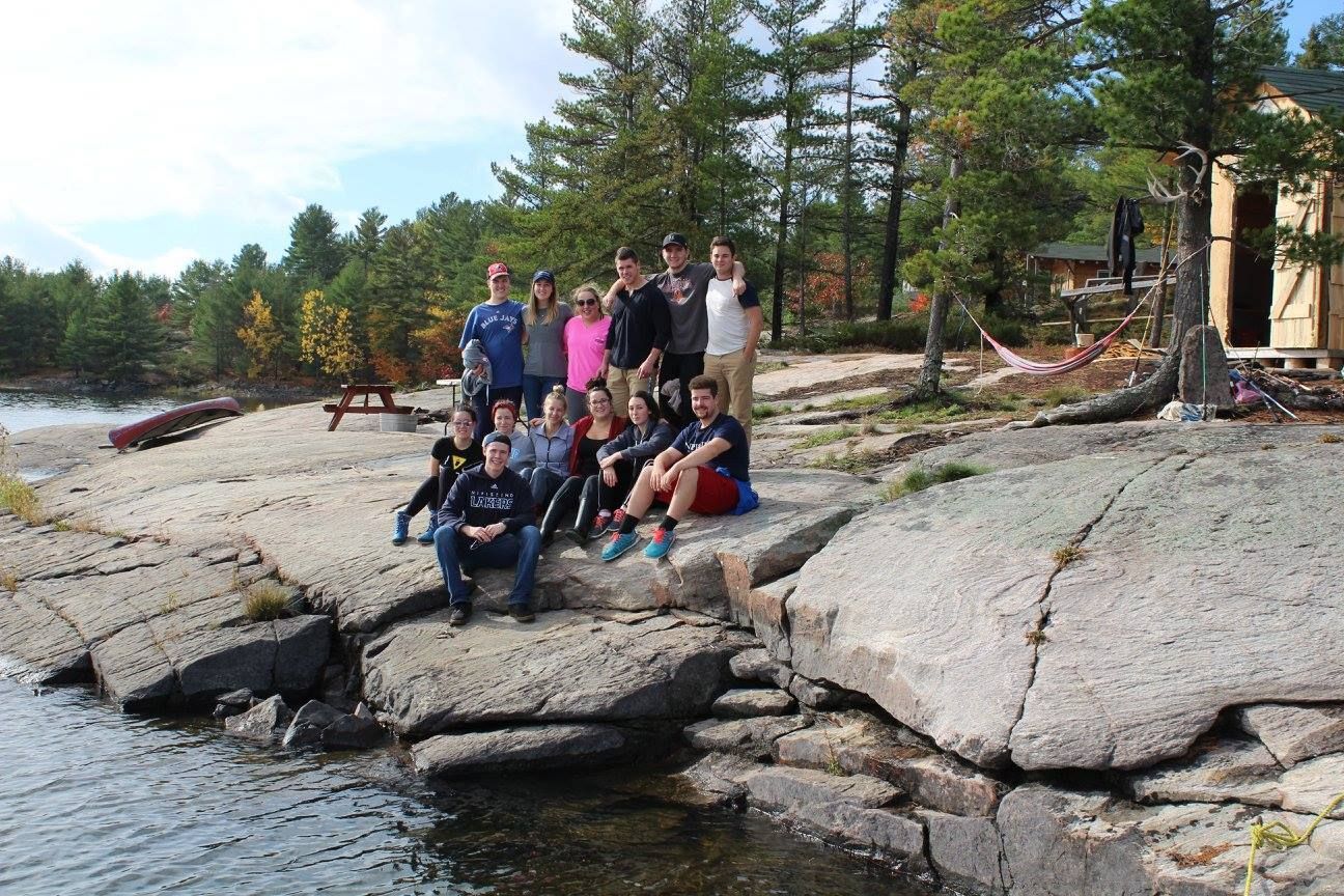 A group of people are sitting on rocks near a body of water.