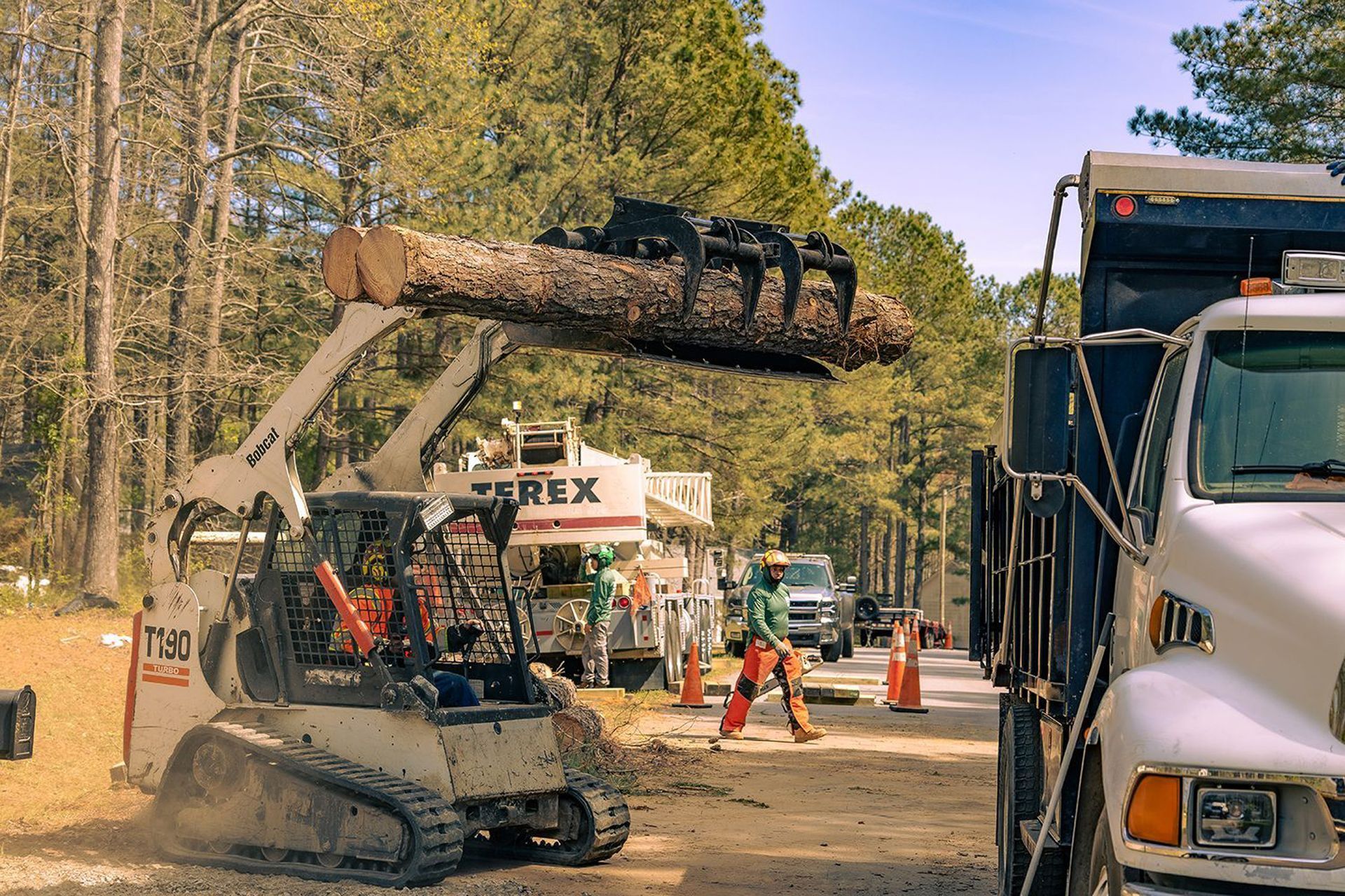A bulldozer is lifting a large log into a truck.