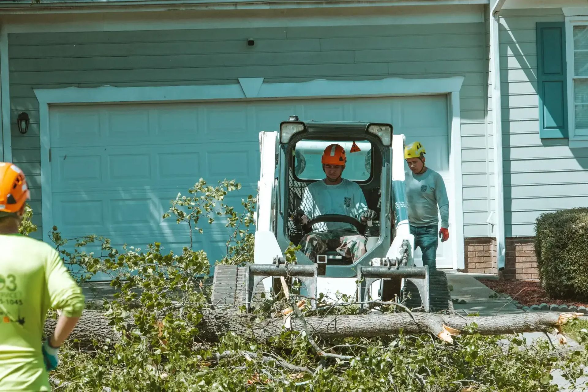 A man is driving a bulldozer in front of a house.