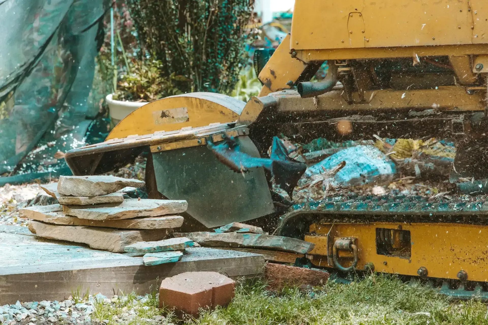 A machine is cutting a tree stump in the grass.
