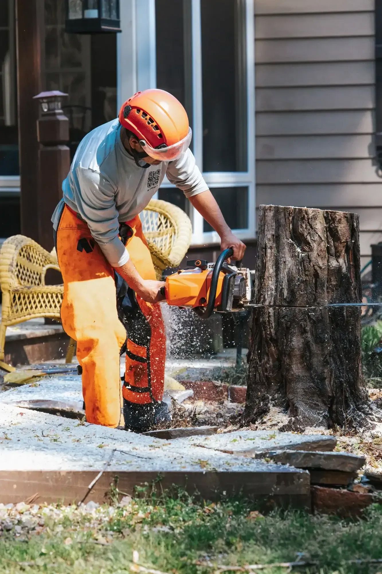 A man is cutting a tree stump with a chainsaw.