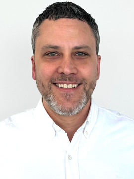 Woman smiling, long brown hair, looking at camera.