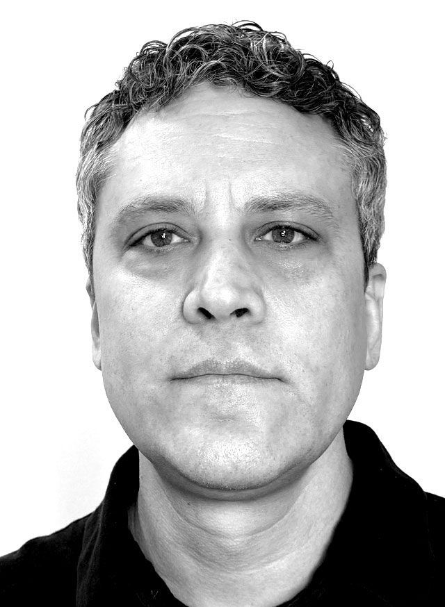 Man with short, graying hair, looking directly at the viewer with a neutral expression.