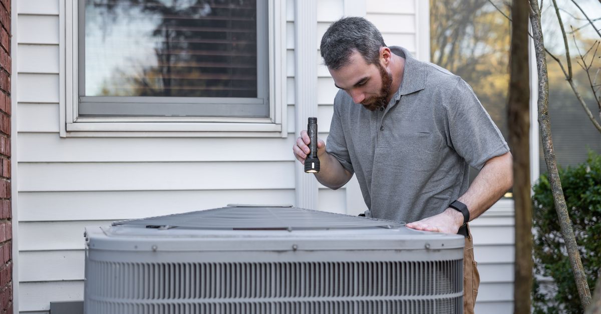 HVAC technician servicing a residential air conditioning system.
