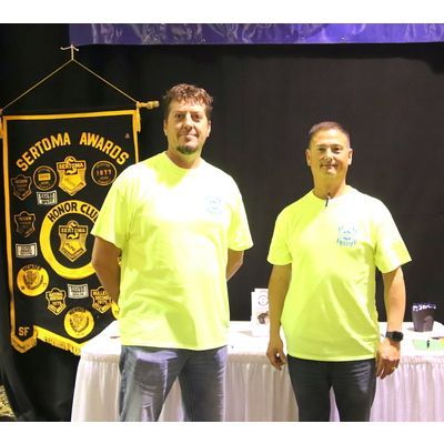 Two men standing in front of a banner that says sertoma awards honor club
