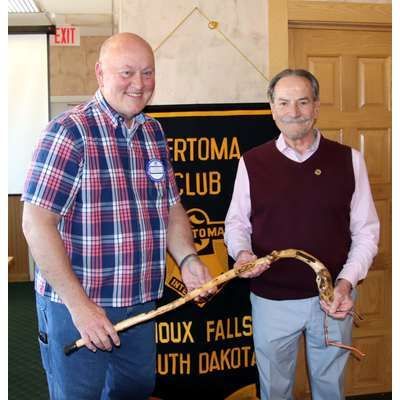Two men are standing next to each other holding a cane in front of an exit sign
