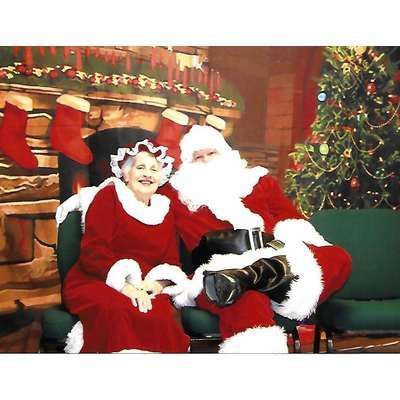 Santa claus and mrs claus pose for a picture in front of a christmas tree