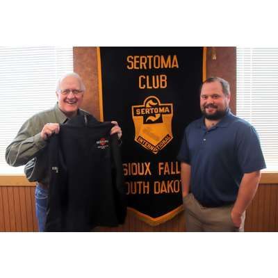Two men are standing in front of a banner that says sertoma club.