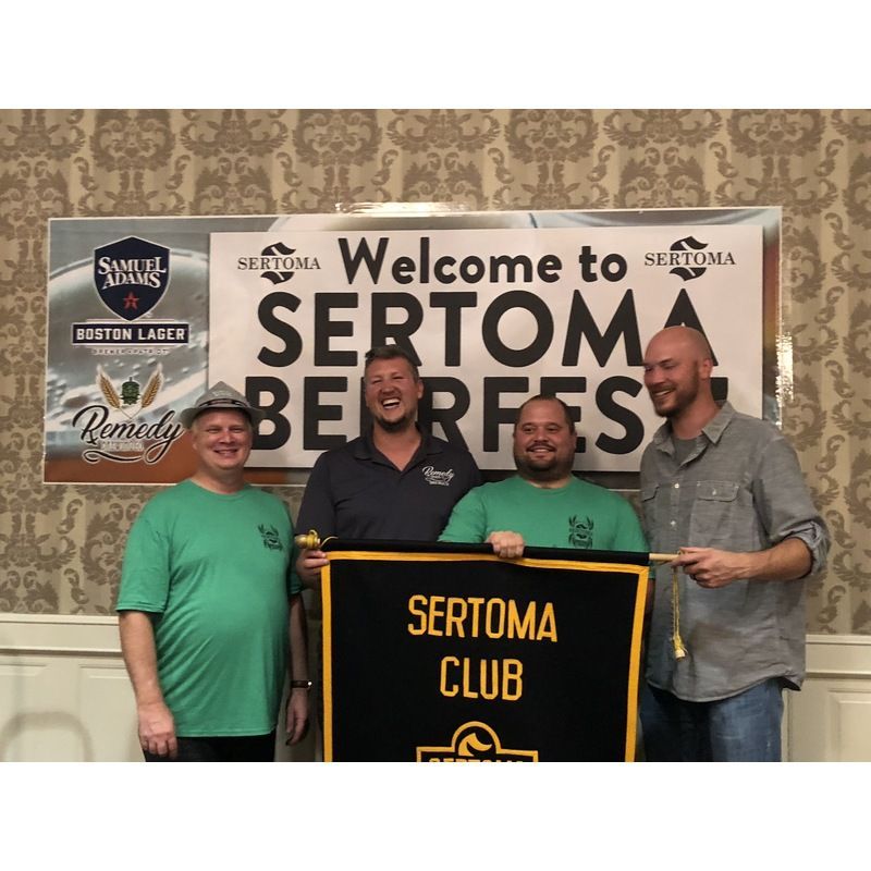 A group of men standing in front of a sign that says welcome to sertoma beerfest