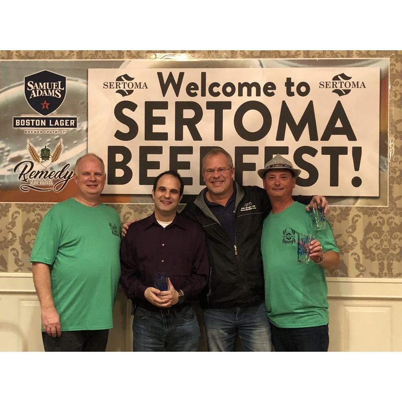 Four men are posing in front of a sign that says welcome to sertoma beer fest