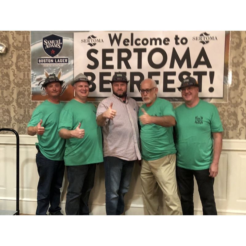 A group of men standing in front of a sign that says welcome to sertoma beer fest