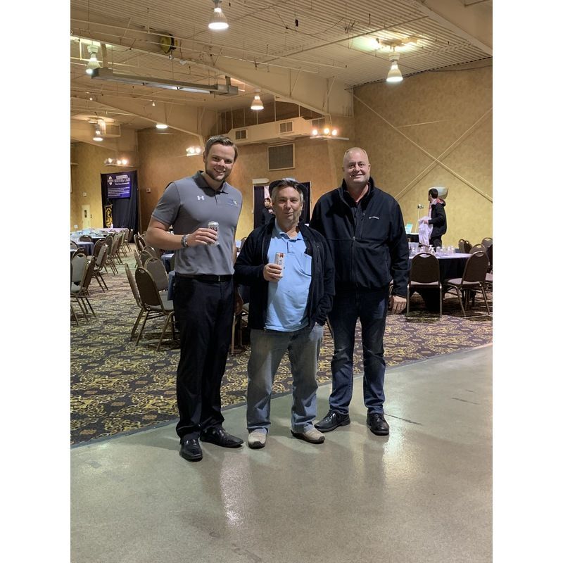 Three men are posing for a picture in a large room