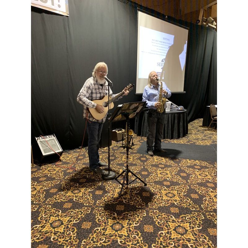 A man is playing a guitar and a man is playing a saxophone on stage.