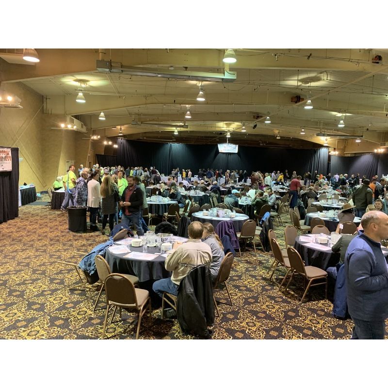 A large room filled with people sitting at tables and chairs.