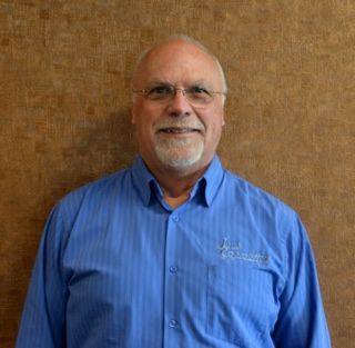 A bald man with glasses and a beard is smiling for the camera.