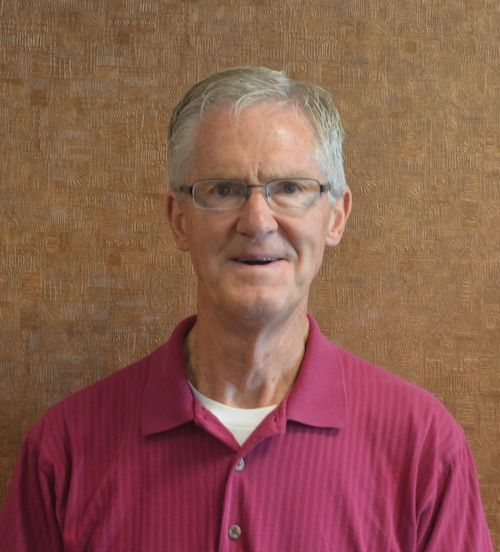 A bald man with glasses and a beard is smiling for the camera.