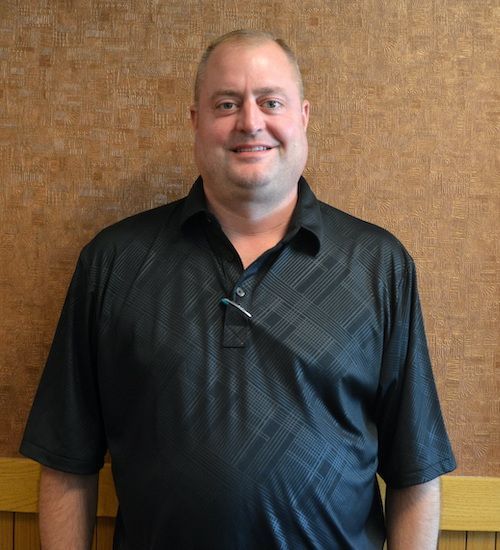 A bald man with glasses and a beard is smiling for the camera.