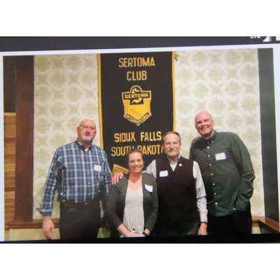 A group of people are posing for a picture in front of a banner that says sertoma club.