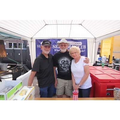 Three people are posing for a picture in front of a sign that says sells soon