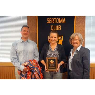A man and two women are standing next to each other in front of a sertoma club banner.