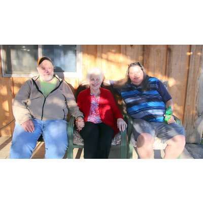 Two men and a woman are sitting on a porch.