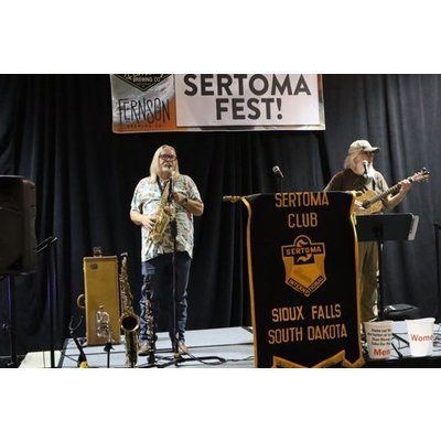 A group of people are playing instruments on a stage at a sertoma fest.