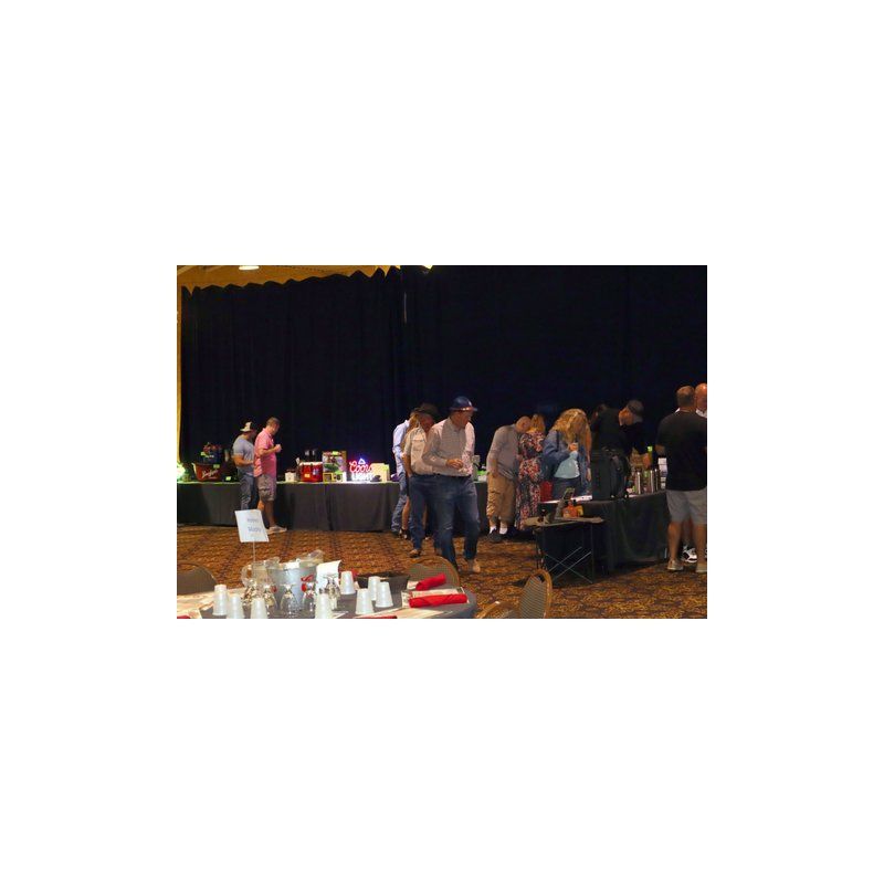 A group of people are standing around tables in a room.