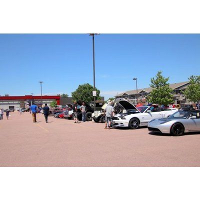 A group of cars are parked in a parking lot at a car show.