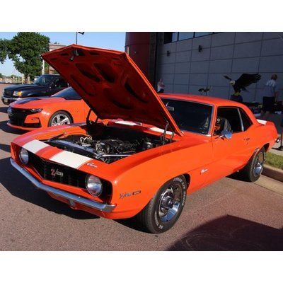 An orange chevrolet camaro with the hood up