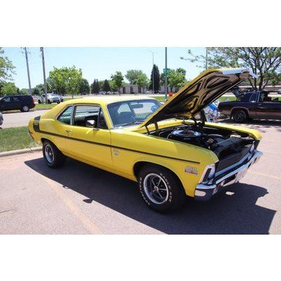 A yellow car with the hood up is parked in a parking lot.