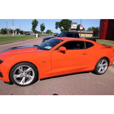 An orange sports car is parked in front of a building