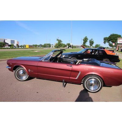 A red mustang convertible is parked next to a black mustang.