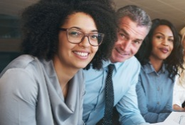 A group of people are sitting at a table and smiling at the camera.