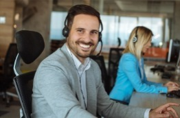 A man wearing headphones is sitting at a desk in front of a computer.