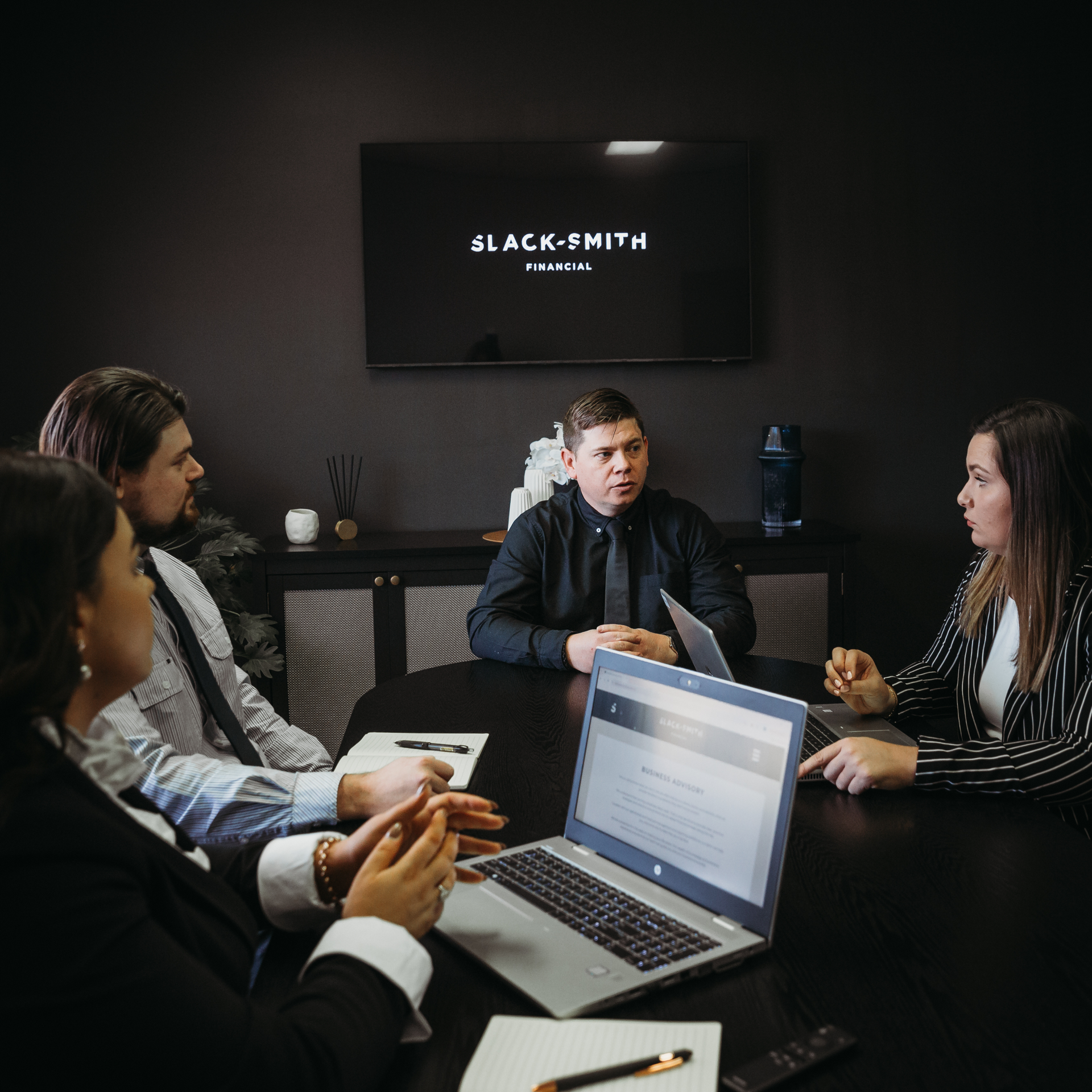 A Group Of People Are Sitting Around A Table With Laptops — Slack-Smith Partners in 