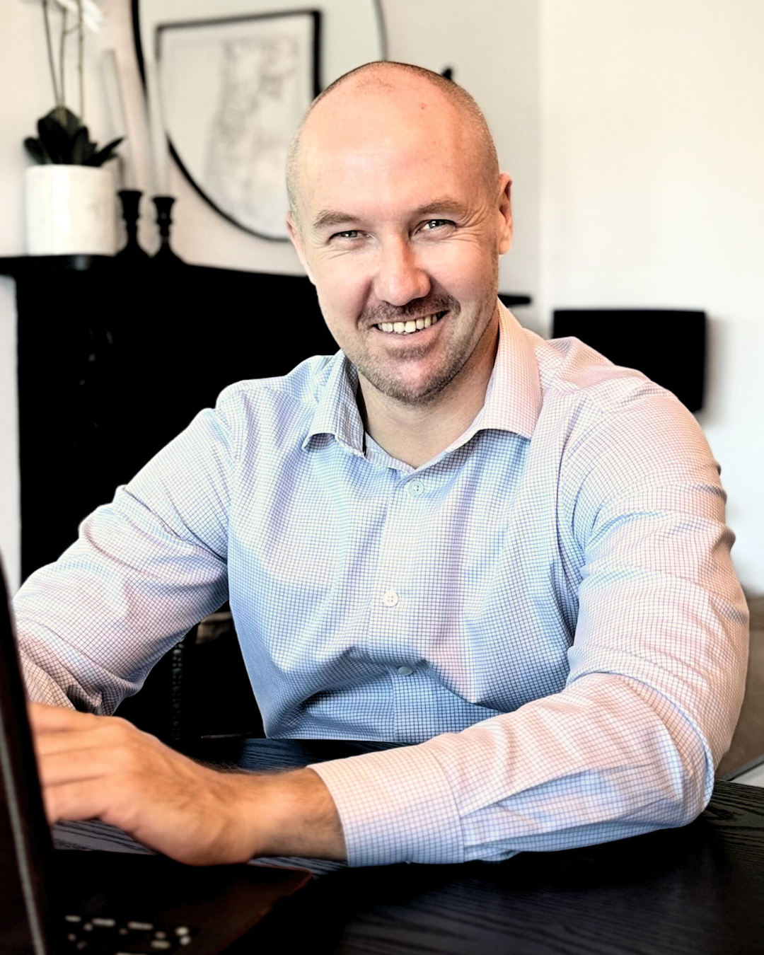 A Man Is Sitting At A Table Using A Laptop Computer — Slack-Smith Partners in Tamworth, NSW