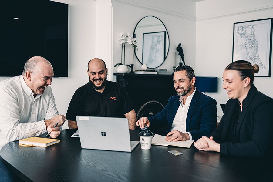 A Group of People Are Sitting Around a Table Looking at A Laptop — Slack-Smith Partners in Gunnedah, NSW