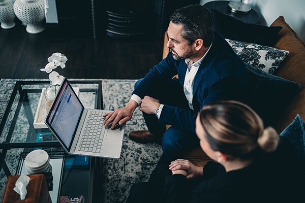 A Man and A Woman Are Sitting on A Couch Looking at A Laptop Computer — Slack-Smith Partners in Tamworth, NSW