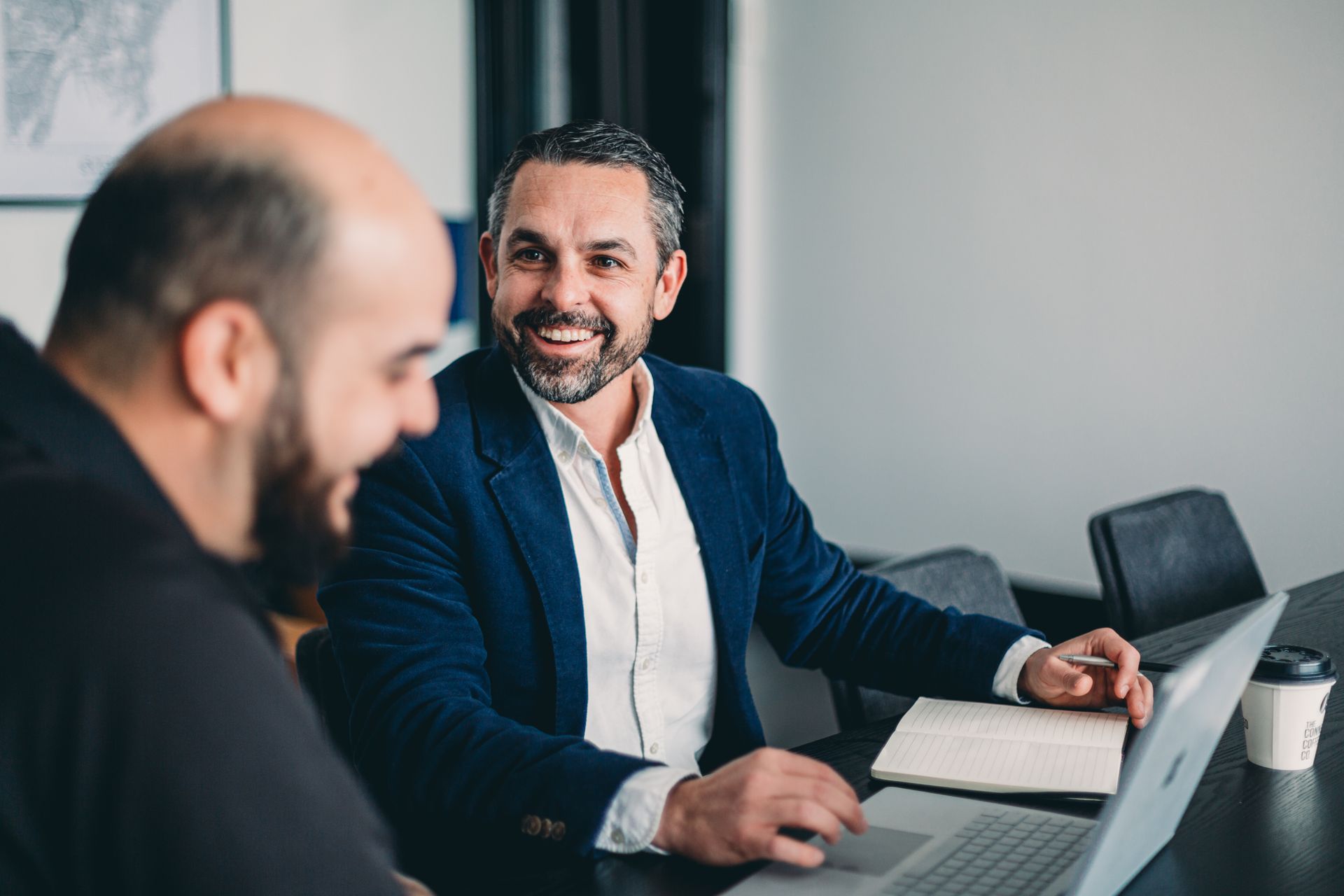 Three Men Are Sitting at A Table Looking at A Laptop — Slack-Smith Partners in Tamworth, NSW