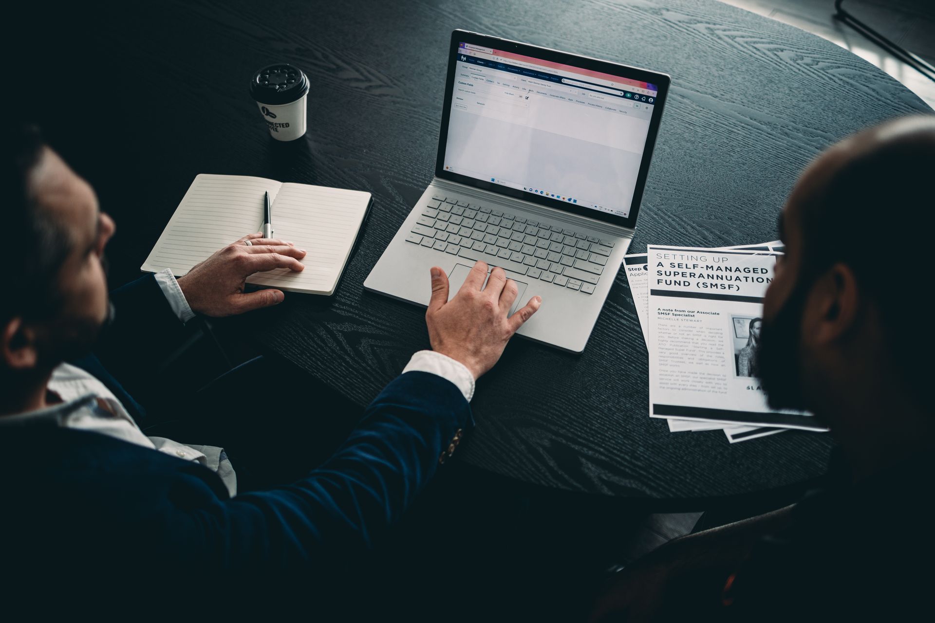 Two People Looking at Laptop Screen on a Black Table — Slack-Smith Partners In Gold Coast, QLD