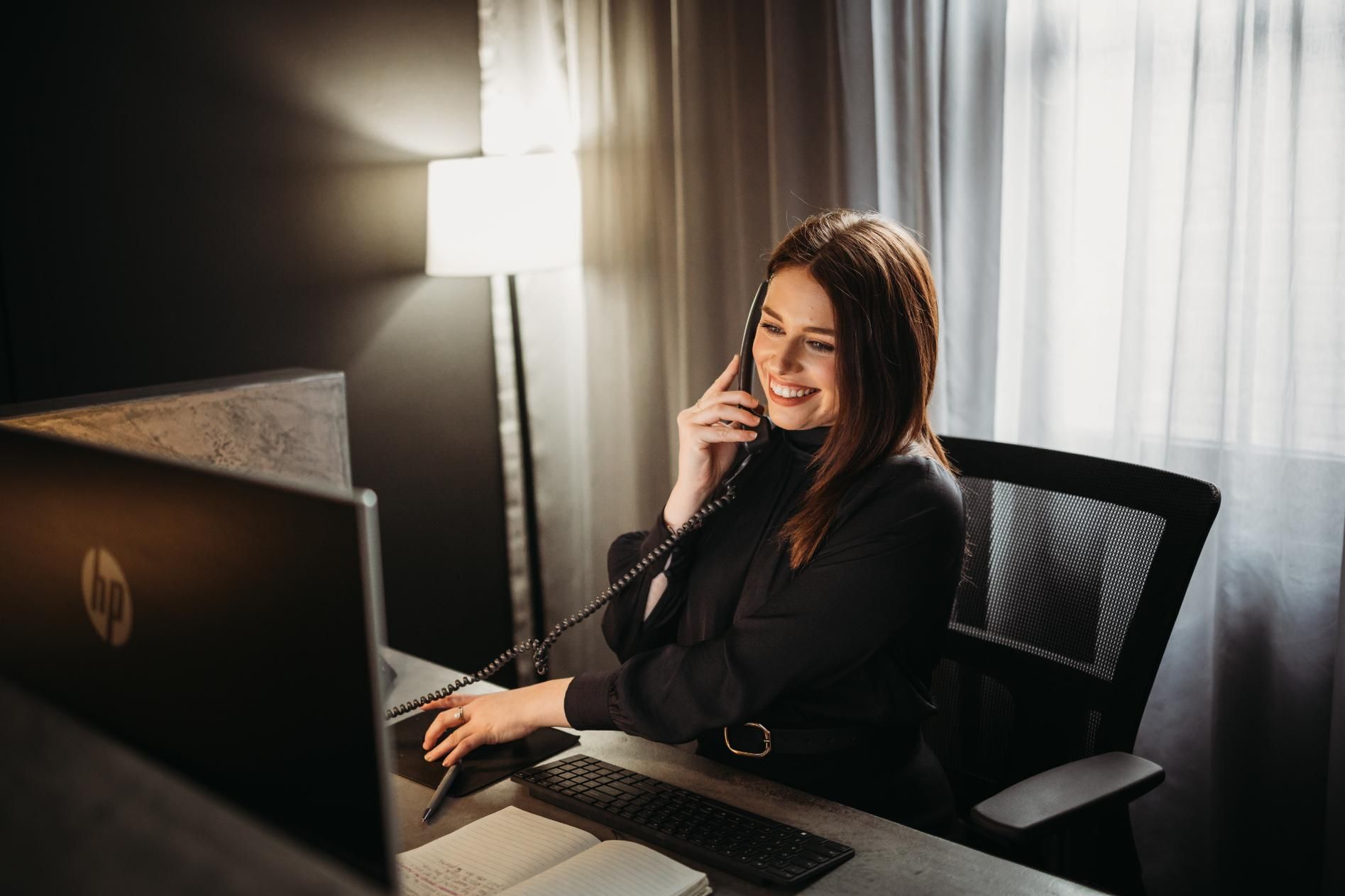 A Woman Is Sitting at A Desk Talking on A Phone in Front of A Computer — Slack-Smith Partners in Tamworth, NSW