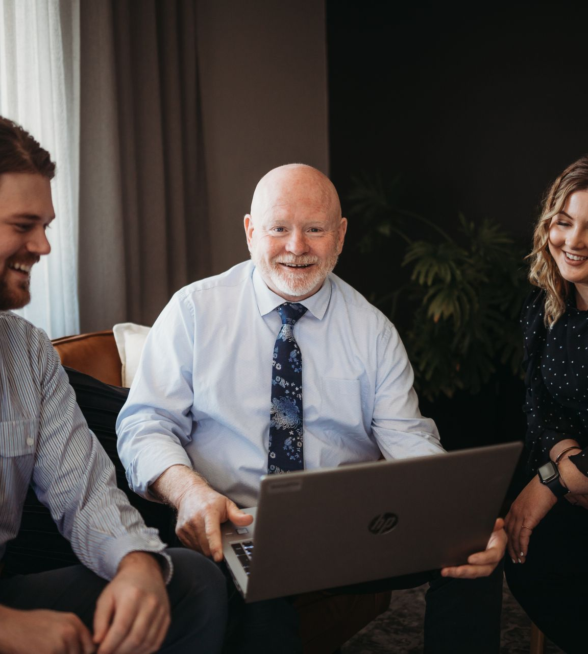 A Three People Smile While Looking at a Laptop in an Office — Slack-Smith Partners in Tamworth, NSW